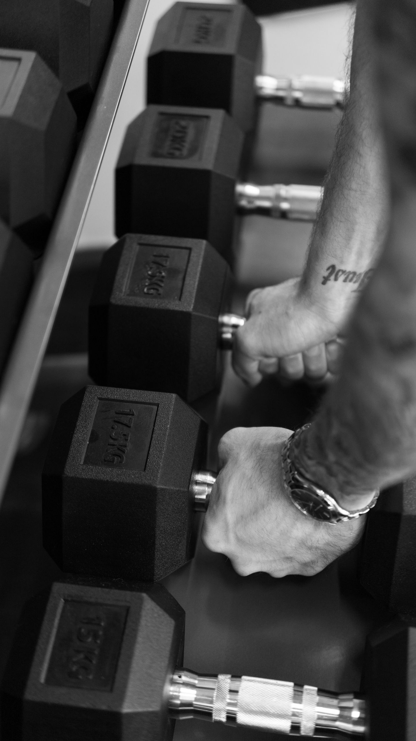 Black and white image of hands gripping dumbbells, showcasing fitness and strength training.