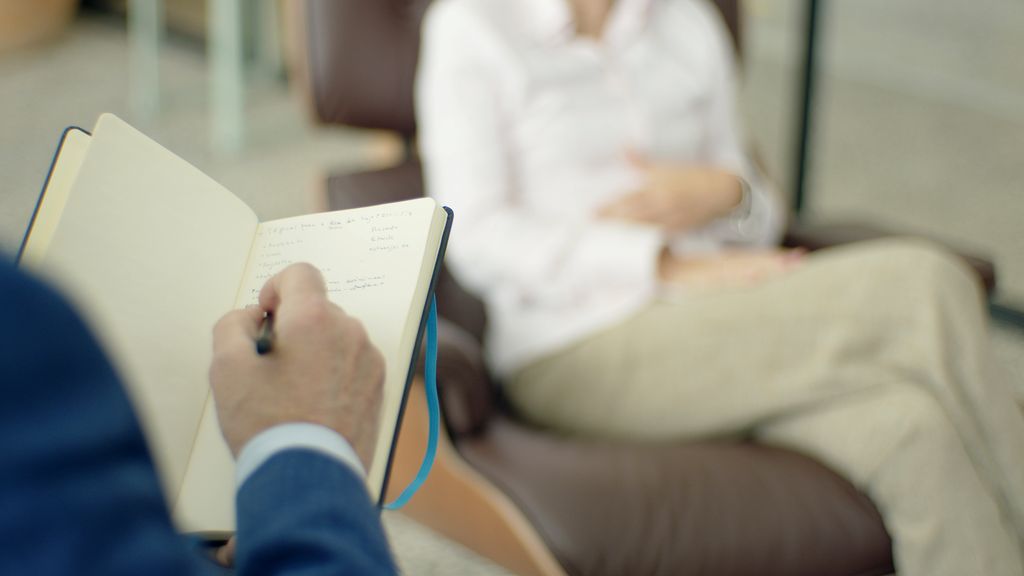 Therapist writing notes during a counseling session with a client.